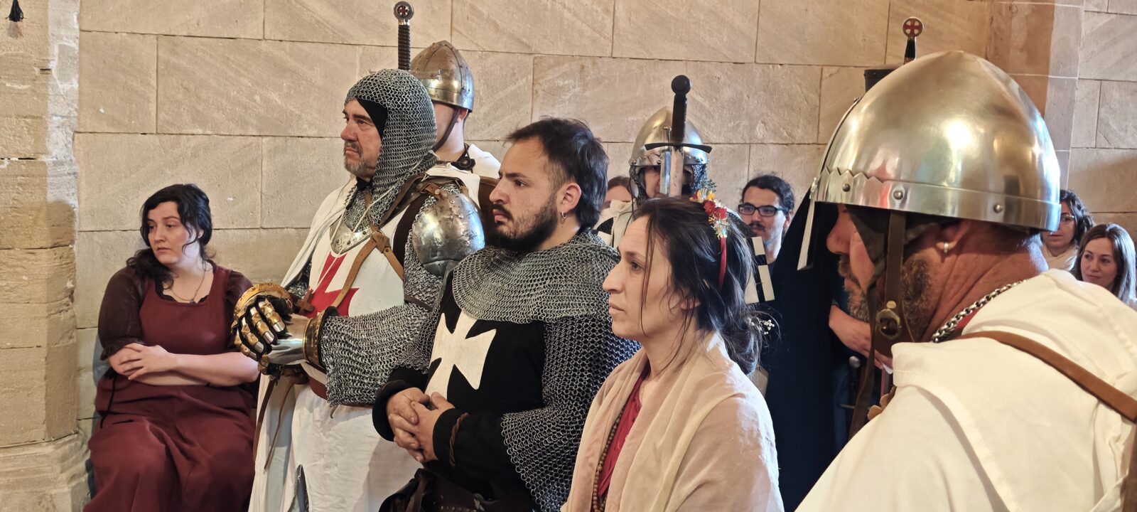 Recreadors amb cotes de malla, elms i vestits d'època esperant dins una sala del castell.